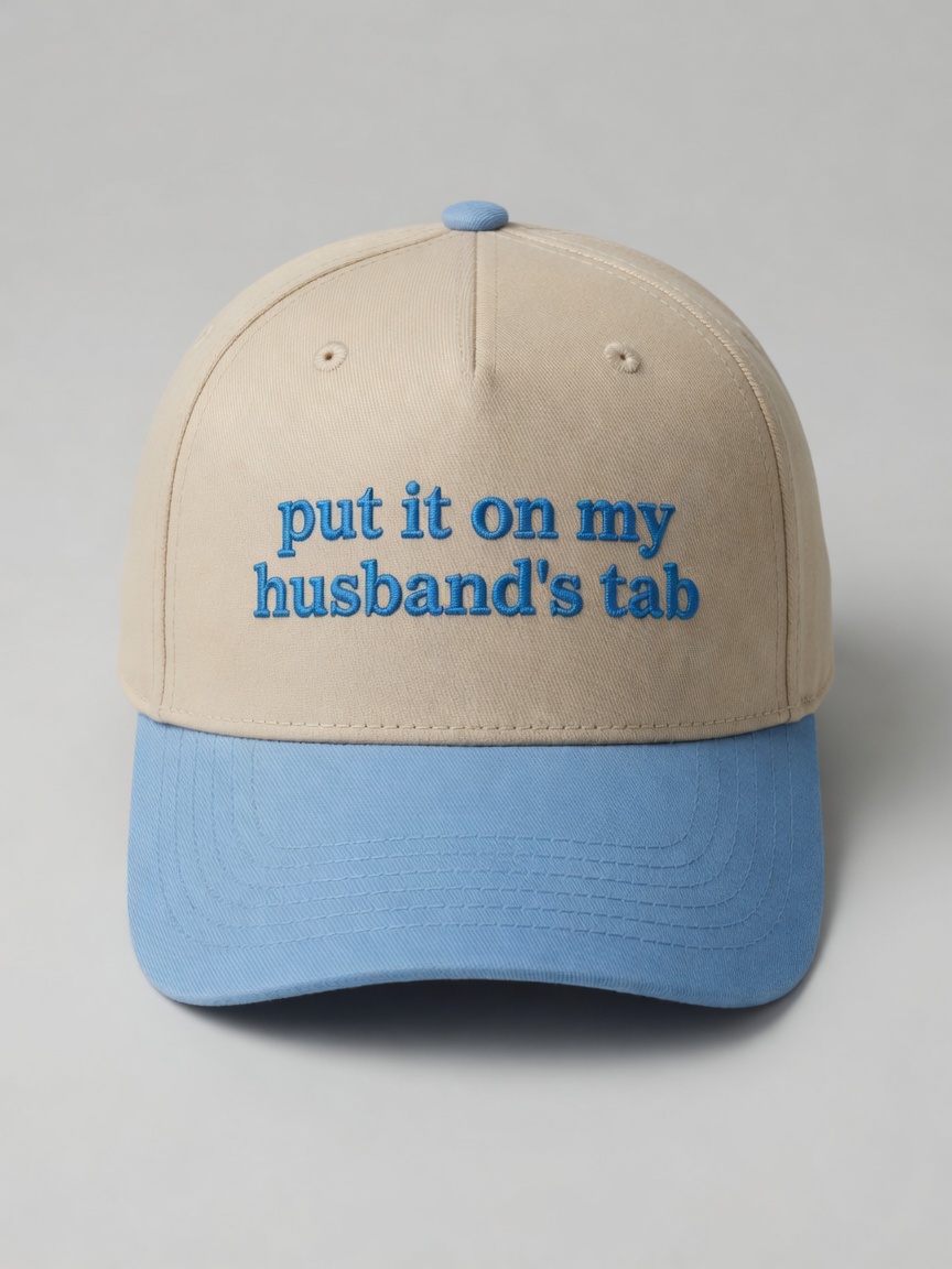 Cream and light blue cap embroidered with the phrase put it on my husband's tab.