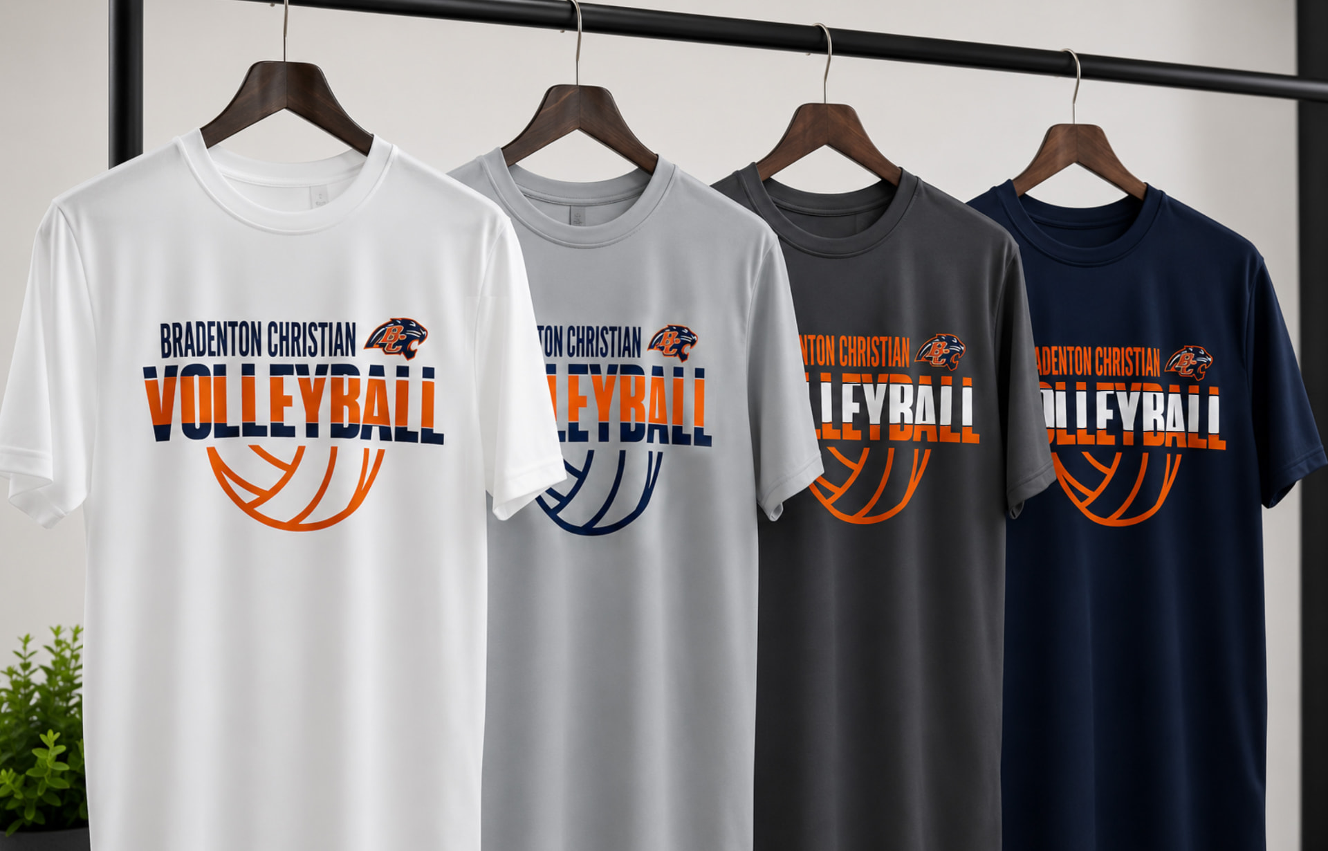 Four performance t-shirts in white, grey, charcoal, and navy hanging on a rack, each with a Bradenton Christian Volleyball graphic and panther logo.