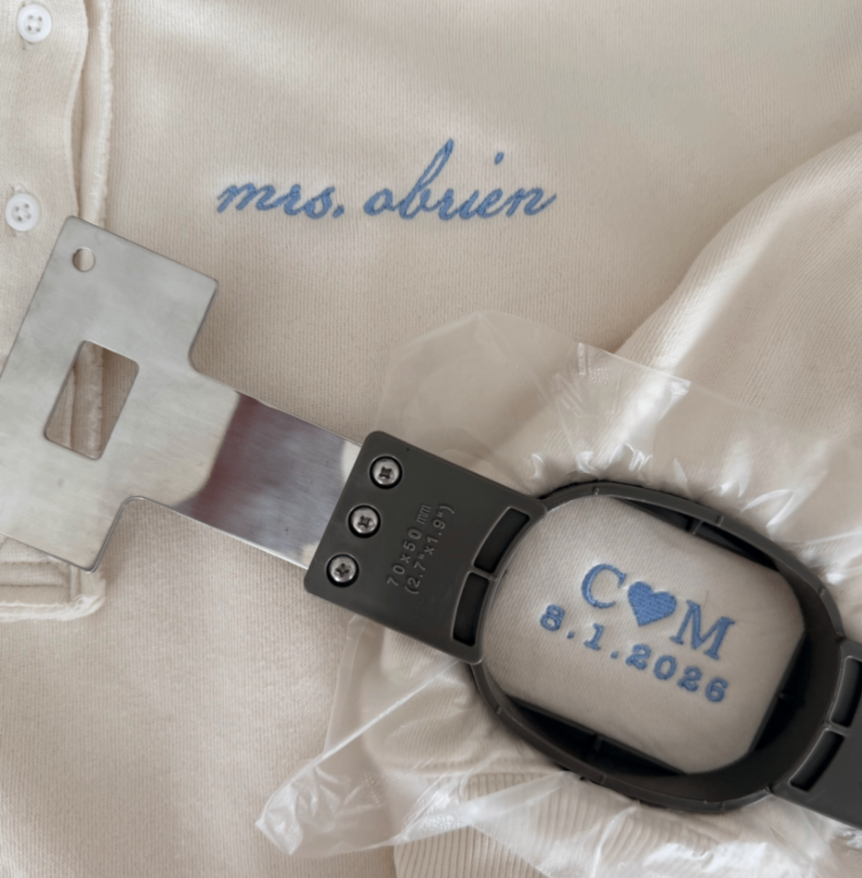 Cream fabric embroidered with mrs. obrien and a blue monogram with wedding date in an embroidery hoop.